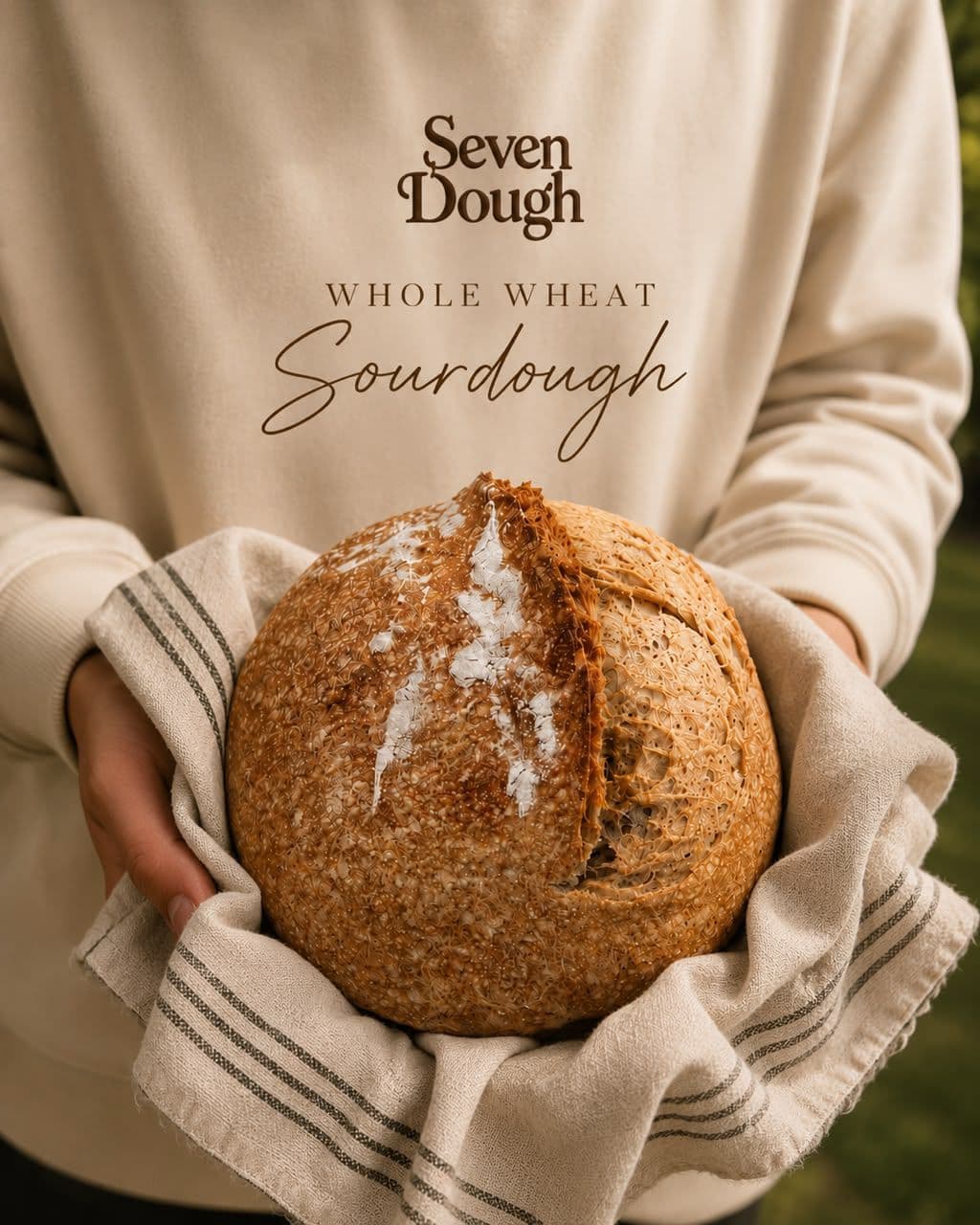 Whole wheat sourdough, scored and blistered, held out in a striped linen cloth